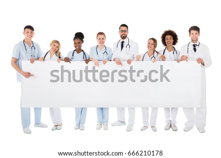 Group Of Happy Medical Team Holding Blank Billboard Over White Background