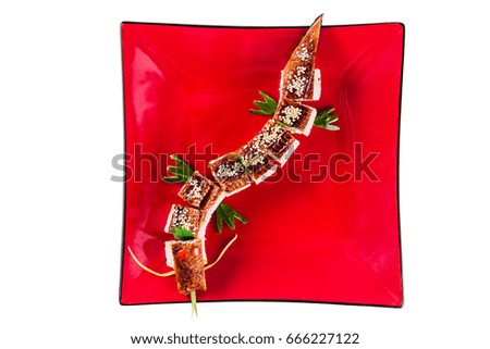 sushi rolls on a red plate on white background isolated (Unagi Dragon). Traditional Japanese cuisine