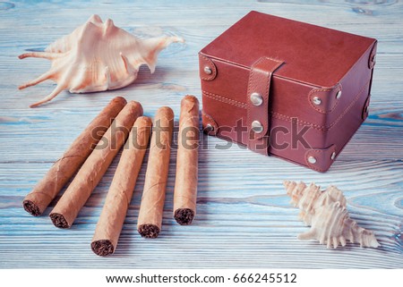 Cuban cigars, seashells and a small chest on a blue wooden table. Memories of vacation
