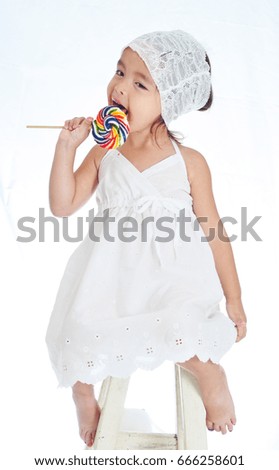 Little girl eating big lollipop, colorful and fun with write background.
