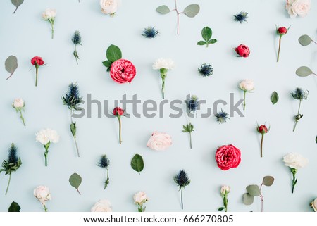 Flowers pattern texture made of beige and red roses, eucalyptus leaf on pale pastel blue background. Flat lay, top view. Floral texture background.