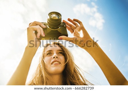 Outdoor lifestyle portrait of pretty young woman having fun on blue sunny sky evening with retro vintage photo camera. Travel photo of photographer. Making pictures. old photocamera