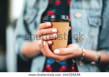 Female hand with paper cup of coffee take away. Royalty-Free Stock Photo #666304648