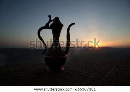 Decorative Arabian vase and jug pictured at sunset with fog