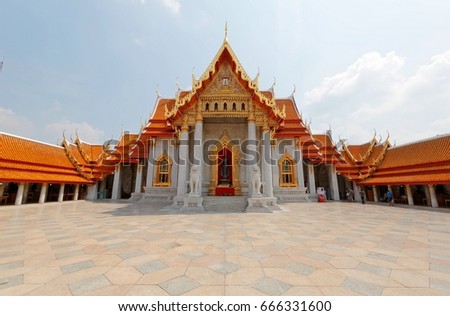 Scenery of Wat Benchamabophit or the famous Marble Temple in Bangkok City, Thailand, a traditional Thai architecture with a decorated gable roof and a courtyard surrounded by corridors under sunny sky