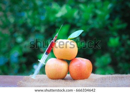 Needle and syringe injected in the apple, Enhanced fruits. Nutrition concept, GMO concept. Background of nature.