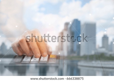 Hand is pressing calculator, There are overlays of buildings and cities, A concept of business, this image focuses on blurring to be used as the background.