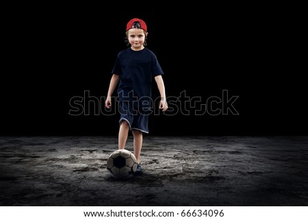 Child football player and Grunge ball on the dark background