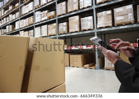  warehouse management  , smart logistic concept. Hand holding tablet or cell-phone  with  application for check order  in smart factory warehouse.industry 4.0 concept , mixed media 