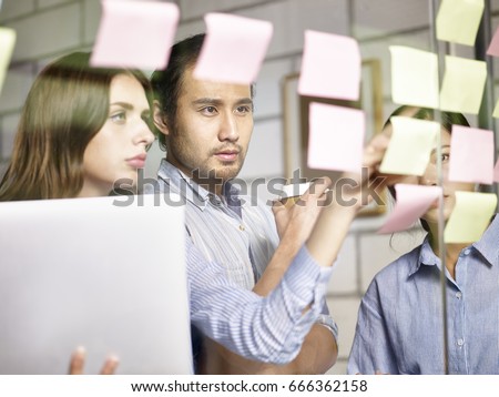 asian and caucasian businesspeople working closely in strategy workshop. Royalty-Free Stock Photo #666362158