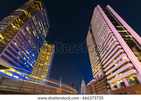 Photo of commercial office buildings exterior. Night view at bottom skyscrapers with light of traffic rush, long exposur in Bangkok.