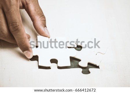 Businessman hand put the last piece of jigsaw puzzle to complete the mission. Business success, solutions and strategy concept,vintage color tone