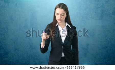 Young beautiful businesswoman with pen writing on the screen.