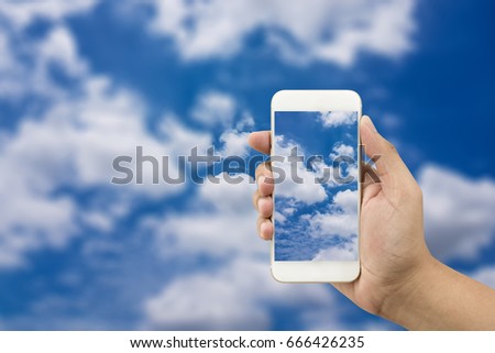 man holding mobile phone, bright sky background with clouds, is like doing business online.