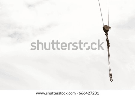 A hook of a construction crane against the sky and clouds. Horizontal orientation. Photo for your design.