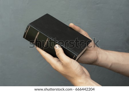 Man holds the Bible on a dark background