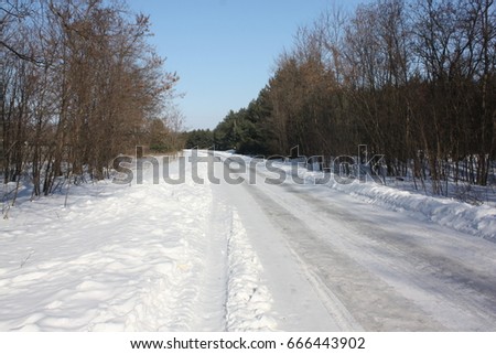 Snow-covered road after last snowfall. Heavy snowfall on a country road. Roadway small size. Wheel tracks on the winter road covered with snow. Photo closeup in winter.