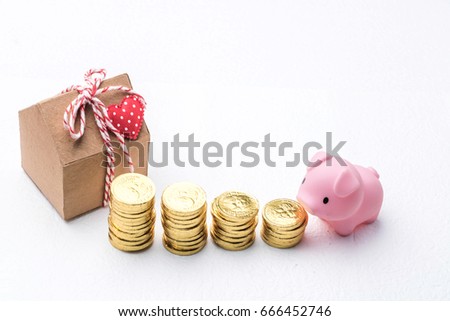 Stacked of money, piggy bank and red heart ribbon on house model isolated on white background. Savings, finances, economy and home concepts.