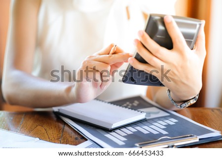 The right hand woman manager holds the pencil. Pressing calculator Monthly sales summary Graph and notebook information available during work.