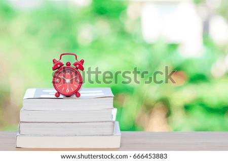 Alarm clock with books on wooden table.