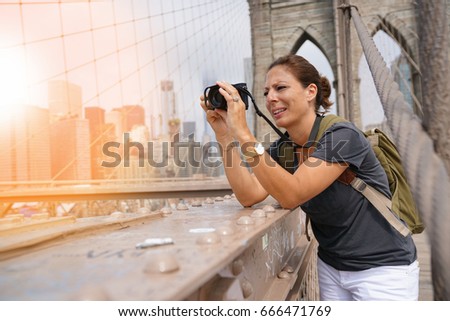 Tourist on Brooklyn bridge taking picture of scenery