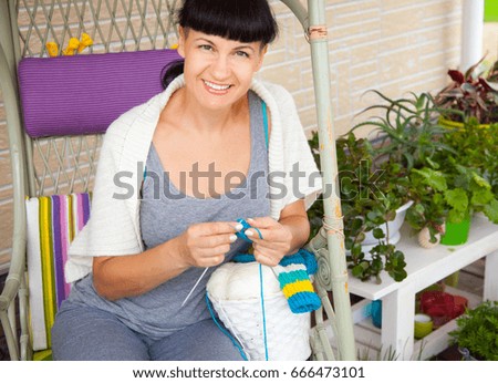 A smiling young woman knits the knitted socks with colored woolen yarn.