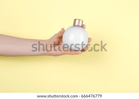 Female hand with bottle of cream for using after shower, on color background