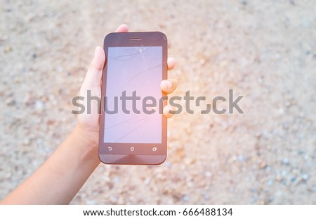 The hands of a girl holding a black smartphone with a broken screen. Damaged, not working. Close up and blur.
