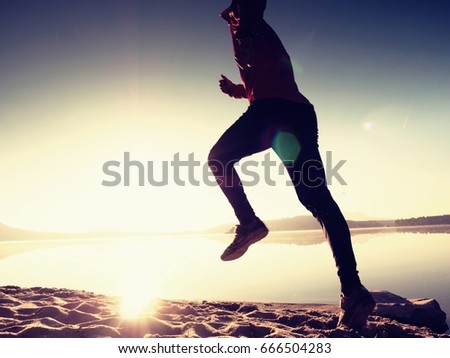 Silhouette of active athlete runner running on sunrise shore. Morning healthy lifestyle exercise on sandy beach.  Man long jumping at ocean, 
sprinting with high  energy in outdoor cardio training .