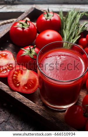 glass of tasty organic tomato juice and fresh tomatoes and herbs on wooden tray in rustic style. Selective focus, healthy lifestyle