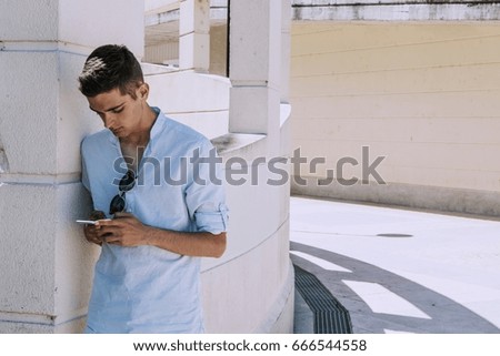 young man to fashion in summer on the street with mobile phone