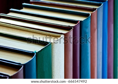 Colorful books are arranged in a row on a dark background (perspective view, background, closeup)