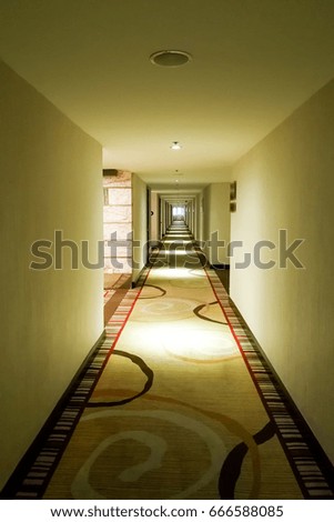 Long dark corridor with intermittent light from ceiling in vertical format