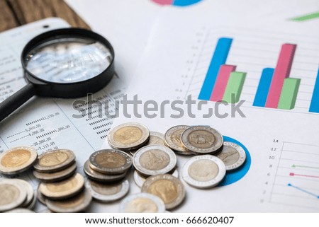 coins on bank account passbook and business chart Magnifying