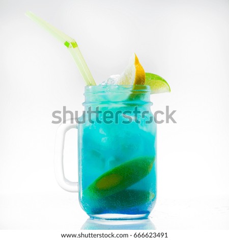 mason jar of cold blue fresh lemonade with lime, lemon and yellow drinking straw on light background. non-alcoholic cocktail