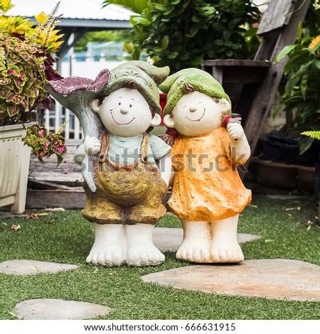 Baked clay doll decorated in garden. Doll ornamental garden. Two statuettes of smiling boy and girl. Smile dolls made from baked clay. Happy dolls for garden decoration-ceramic dolls. vintage film to
