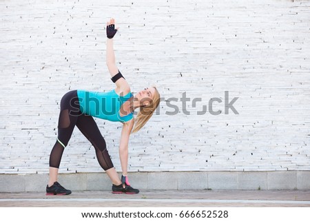 Portrait of fit and sporty young woman doing stretching in city