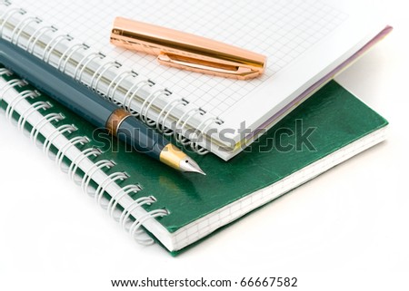 The ink pen lying on a green notebook isolated on a white background