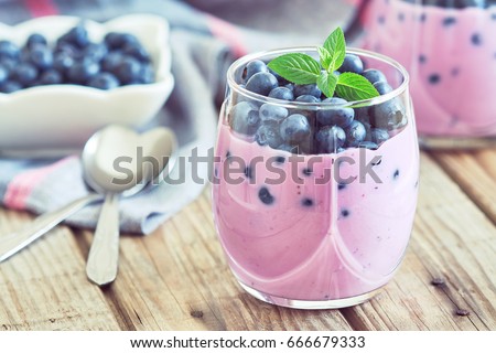 Blueberry yogurt served with fresh blueberries and mint leaves Royalty-Free Stock Photo #666679333