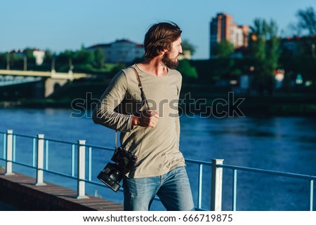 Fashionable photographer walking around the city with a retro photo camera