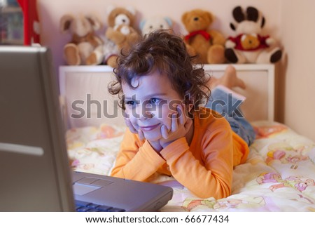 little girl, 5- 6 years old, enjoying her favorite cartoon on a laptop