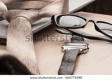 Fashion and business. Close-up sunglasses, tie and watch, on a wooden table, as background.