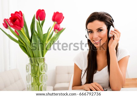 Portrait of a young beautiful woman listening to music with tulips in the background
