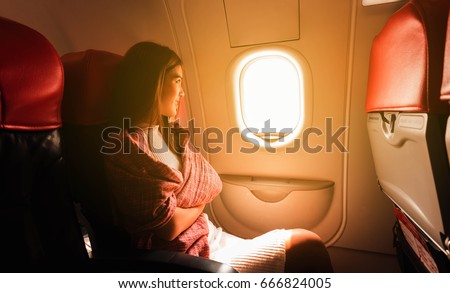 Young beautiful woman sit by window of airplane during flight Royalty-Free Stock Photo #666824005