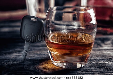 Glass of whiskey and car keys on wooden bar table