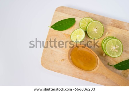 Honey in a spoon and lemon sliced on a wooden cutting board. Royalty-Free Stock Photo #666836233