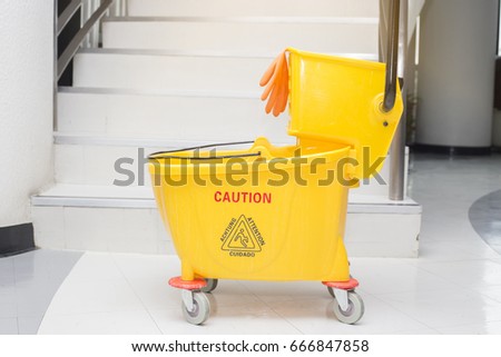 Yellow mop bucket and set of cleaning equipment in the office