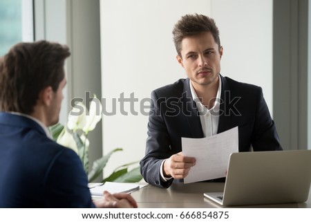 Distrustful businessman holding document at meeting, looking at partner with doubt suspicion, recruiter reads bad resume, caught applicant being dishonest at job interview, shady deal, contract fraud  Royalty-Free Stock Photo #666854875