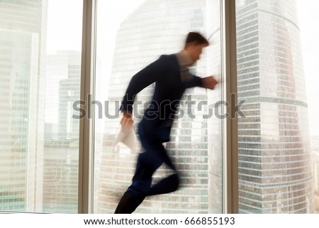 Busy businessman hurrying up to come at meeting on time in office building, blurred silhouette running in hurry along hallway, looking on wristwatch on the move, window city view at background  Royalty-Free Stock Photo #666855193