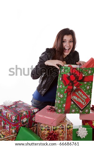 A woman is by a stack of presents and very excited.
